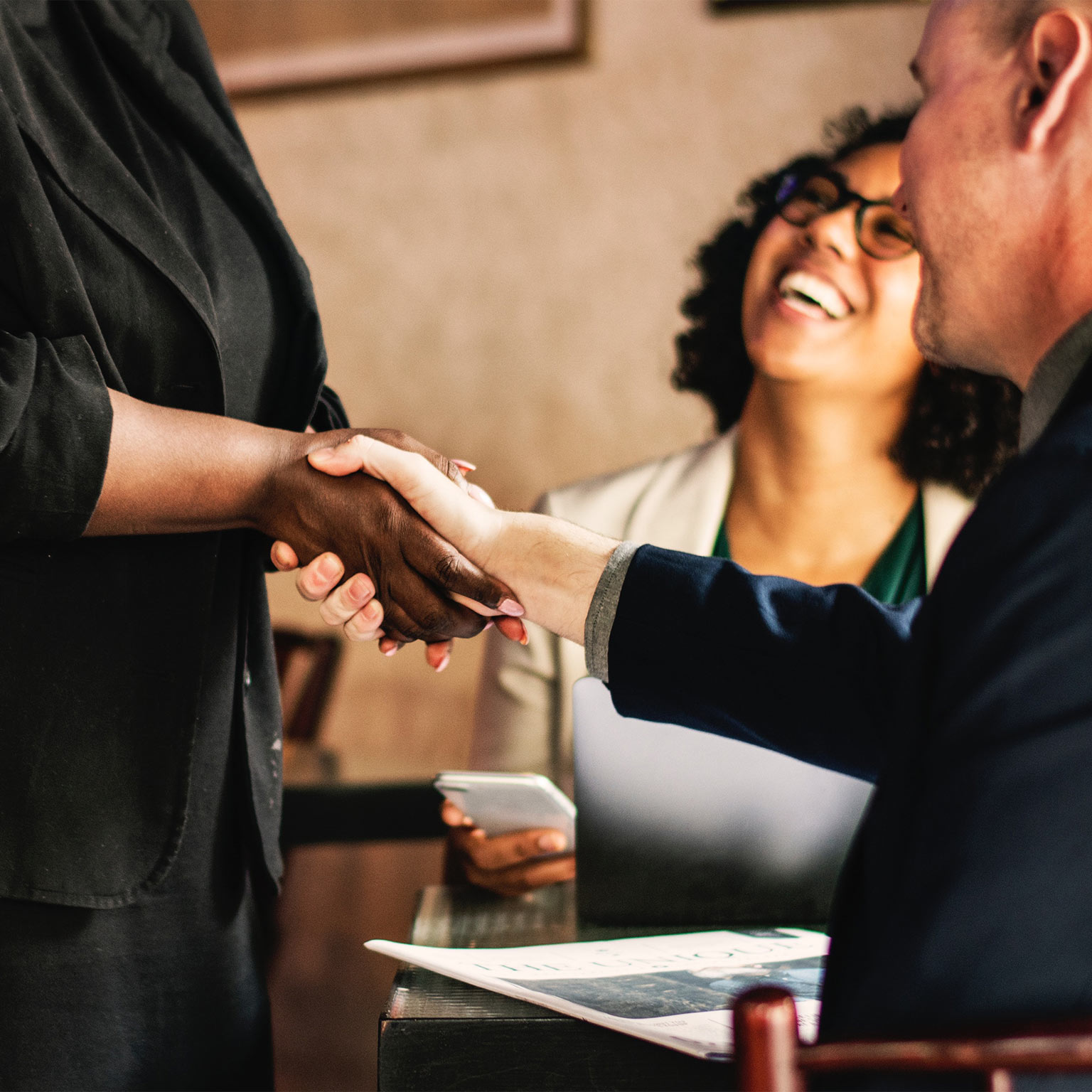 Three people in business attire meeting at a restaurant