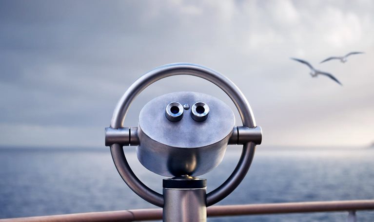 Telescope on a ship with two birds flying over the water in the background