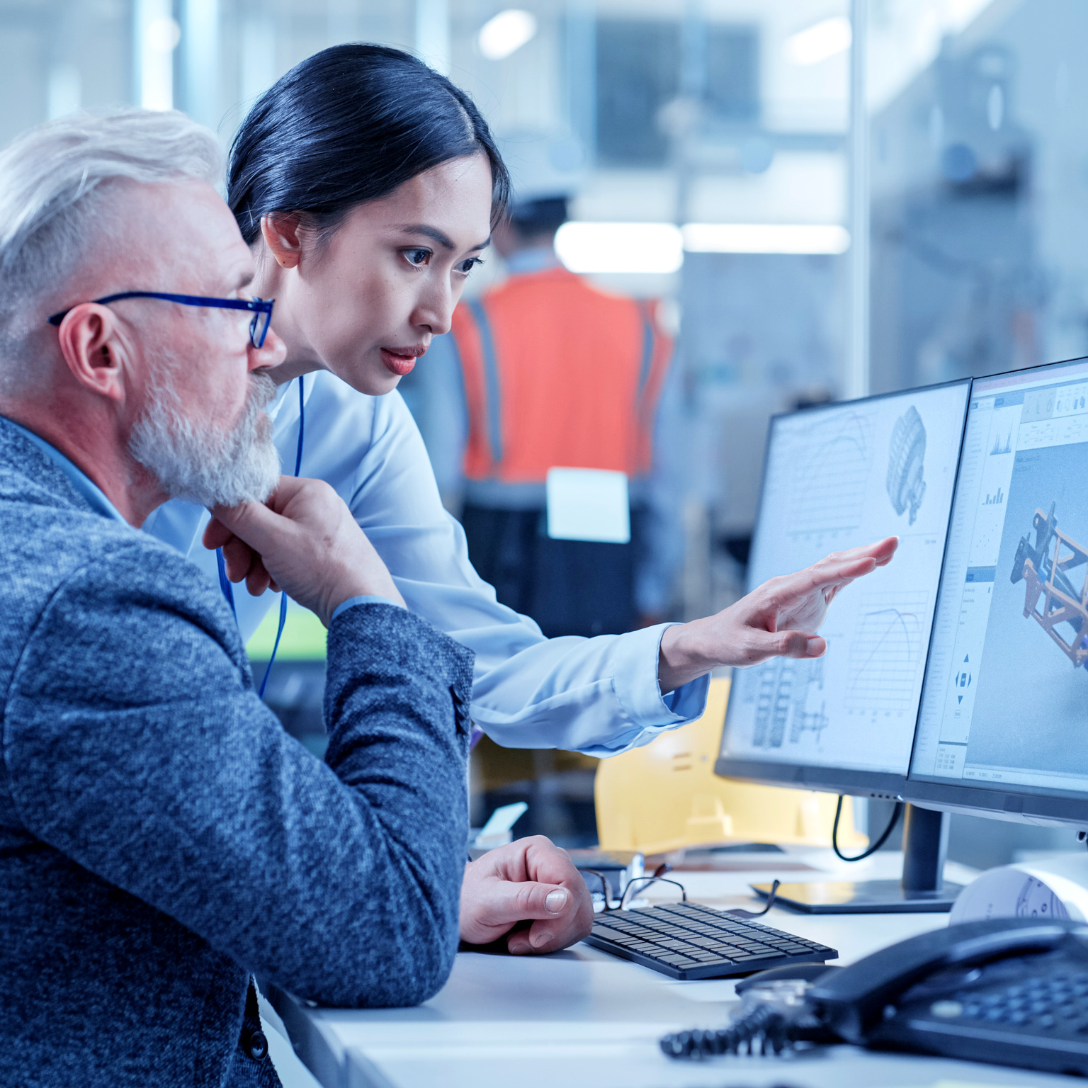 Asian female technician discusses work with middle aged designer.