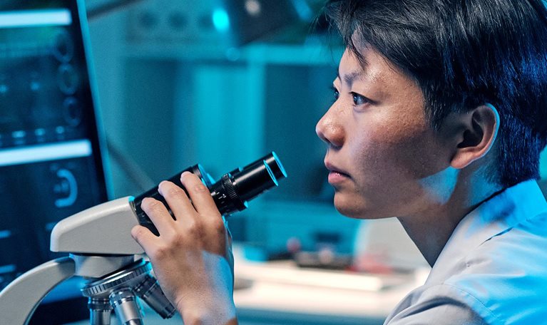 Young serious female scientist looking at computer screen